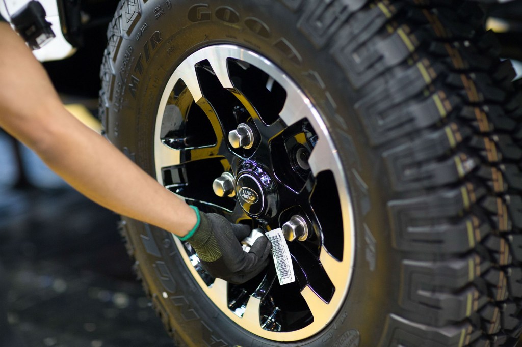A JLR employee fits lug nuts on a 2015 Land Rover SUV