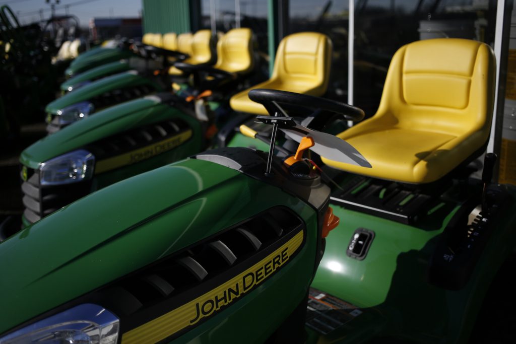 A group of John Deere riding lawn mowers in front of a store