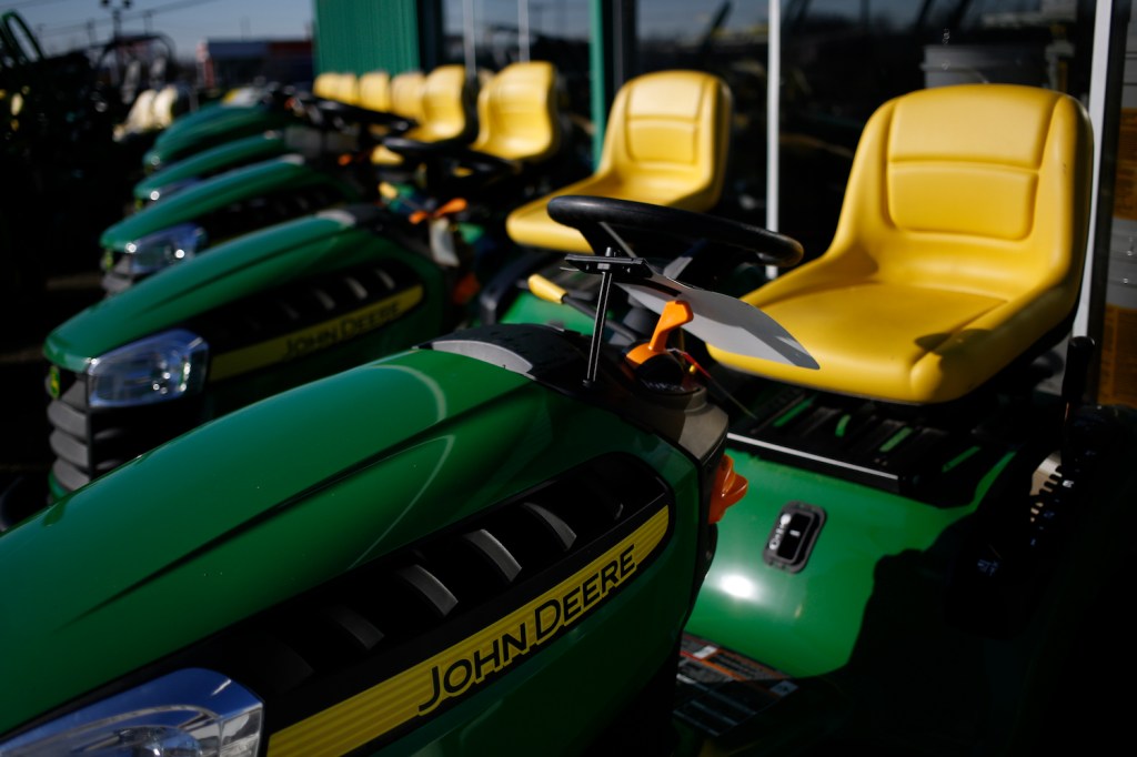 Pictured are John Deere riding lawn mowers. Before buying a lawn mower, consider the best lawn mower features.