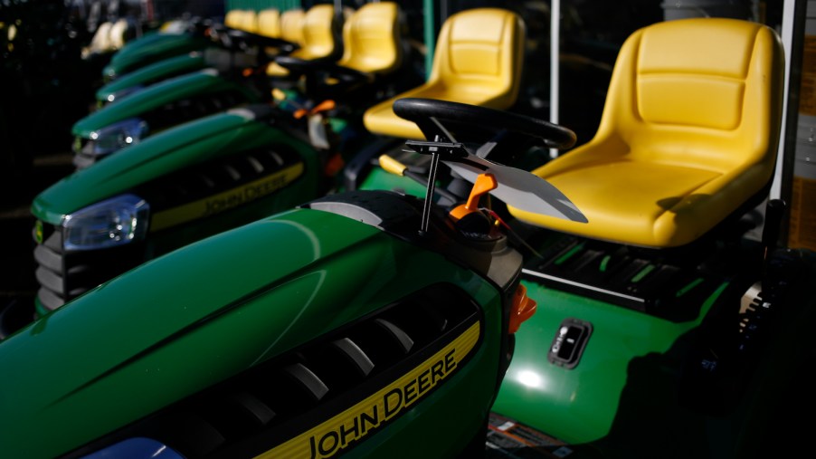Pictured are John Deere riding lawn mowers. Before buying a lawn mower, consider the best lawn mower features.