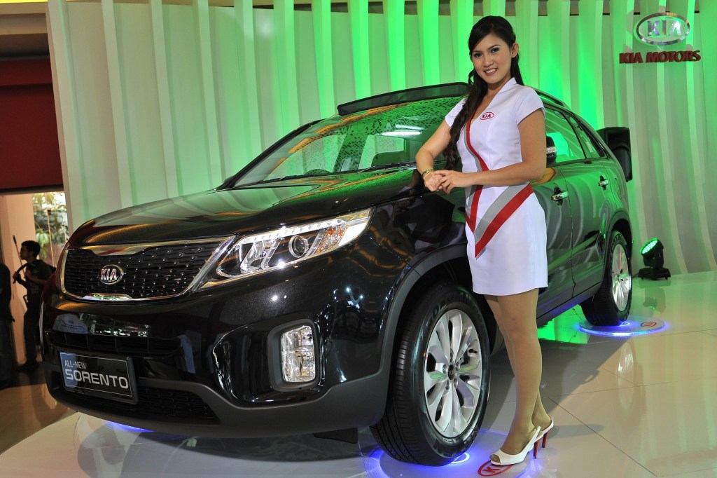 A model stands next to a black 2013 KIA Sorento on display at The 21st Indonesia International Motor Show