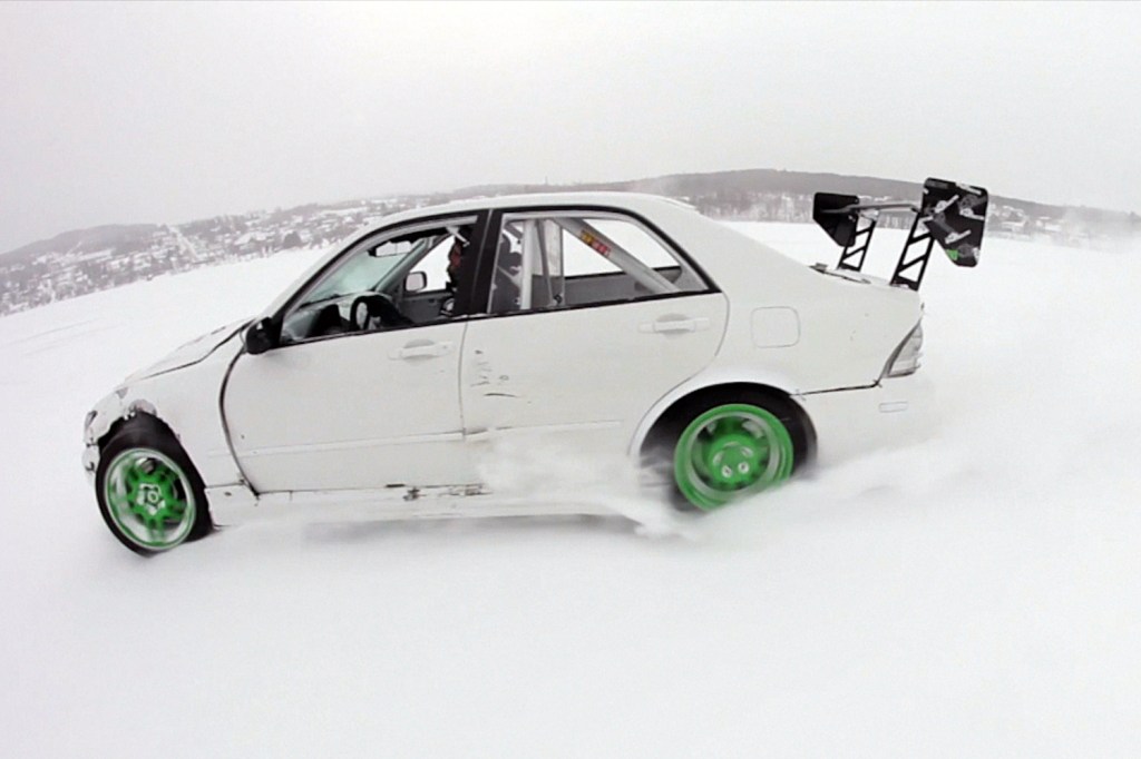 A modified white Lexus IS300 sedan drifting on a frozen lake