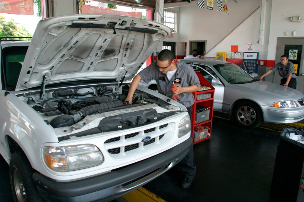 A mechanic changes the oil on a car.