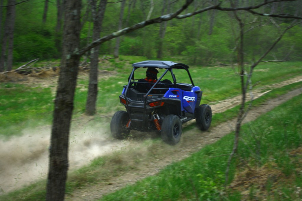 UTV buggy racing through the woods kicking up a ton of dust