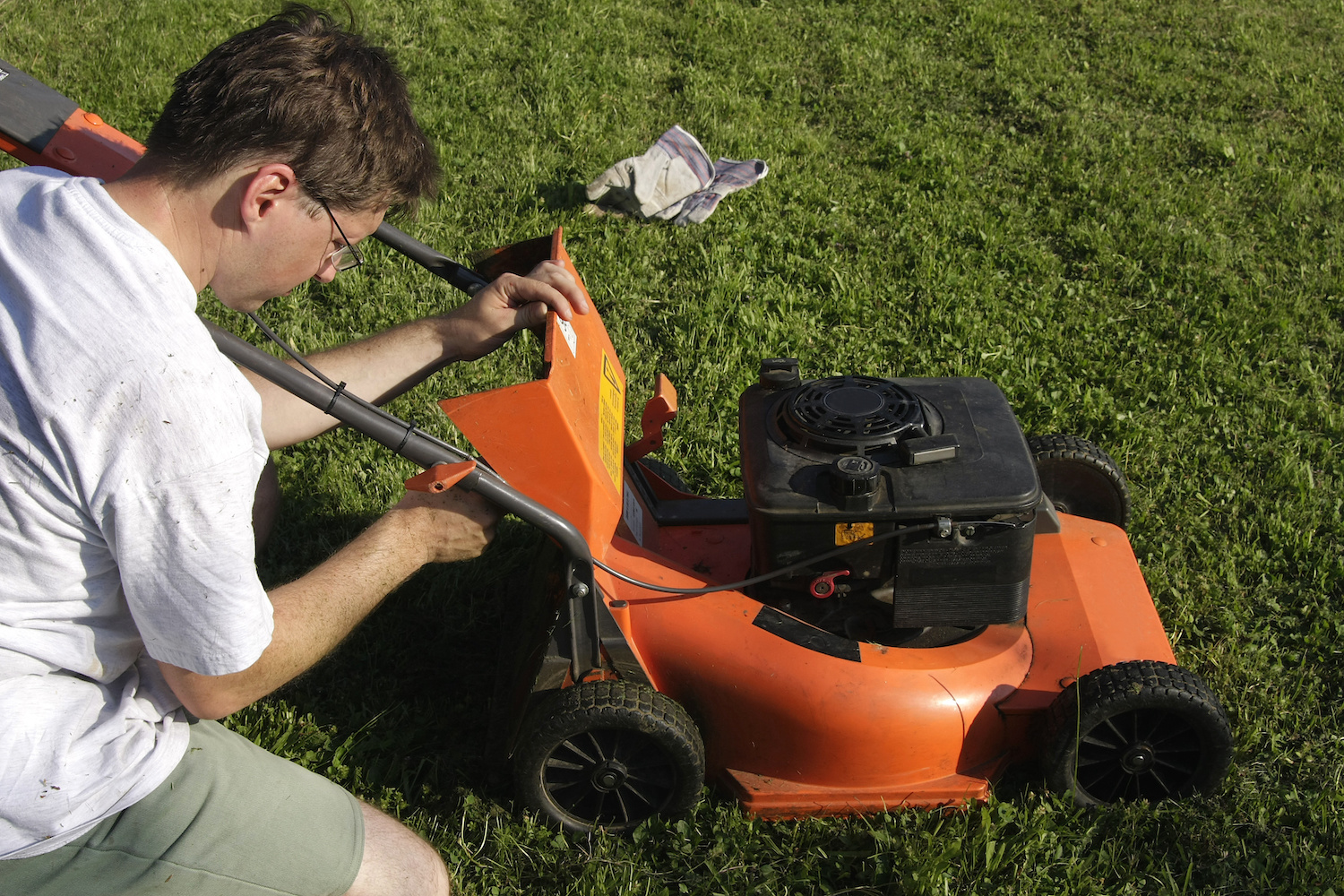 A man performing maintenance on a lawn mower
