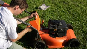 A man performing maintenance on a lawn mower