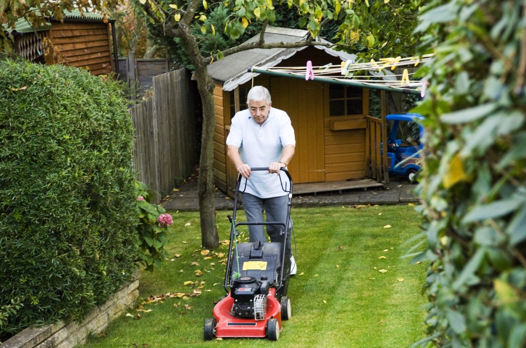 A man mowing a small yard with a push mower