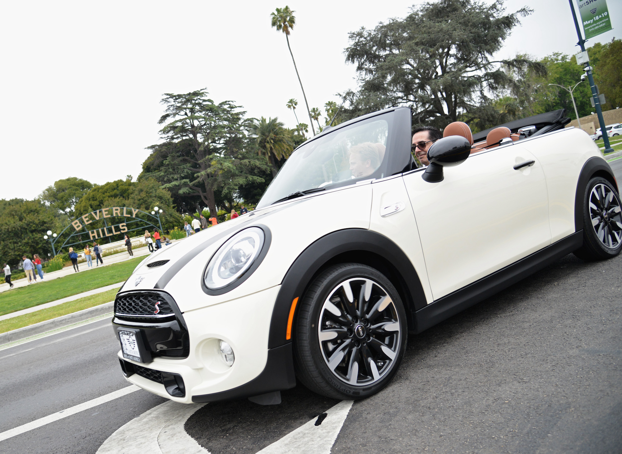 A white Mini Cooper convertible drives past Beverly Gardens Park at the 2019 BritWeek Car Rally on April 28, 2019, in Beverly Hills, California