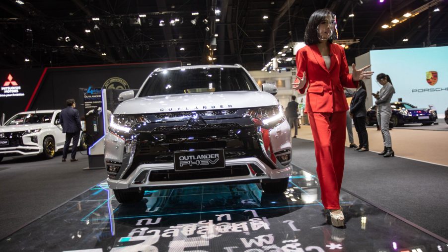 A model stands next to a silver Mitsubishi Outlander PHEV at the Mitsubishi stand during the 42nd Bangkok International Motor Show