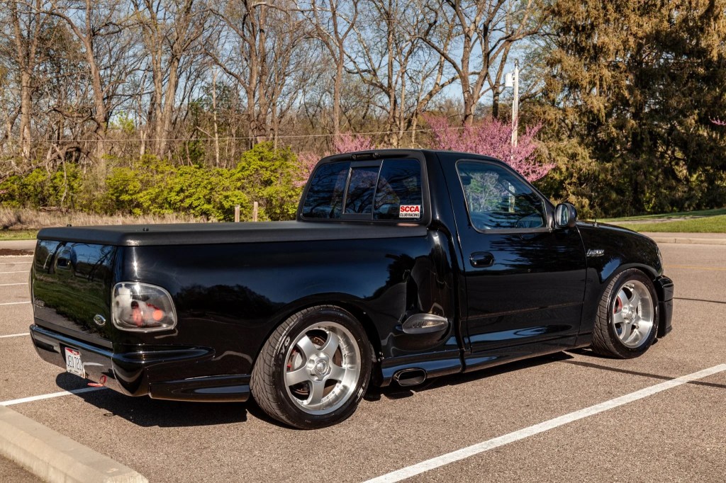 The rear 3/4 view of a black modified 2002 Ford F-150 SVT Lightning in a parking lot
