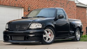 A black modified 2002 Ford F-150 SVT Lightning by a brick building
