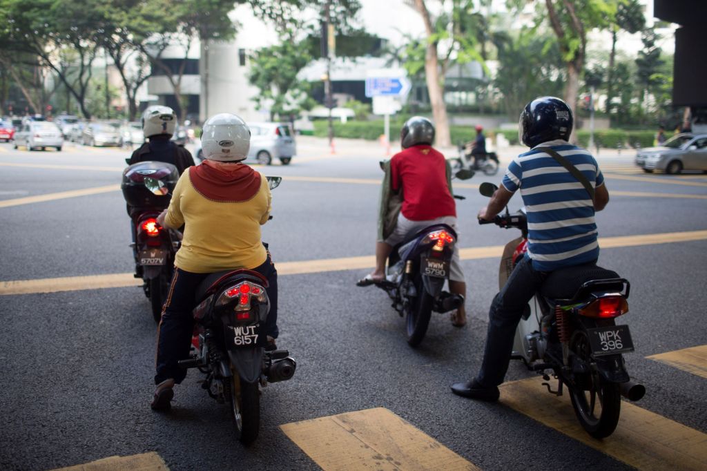 Motorcycle riders in Malaysia wait at a red light