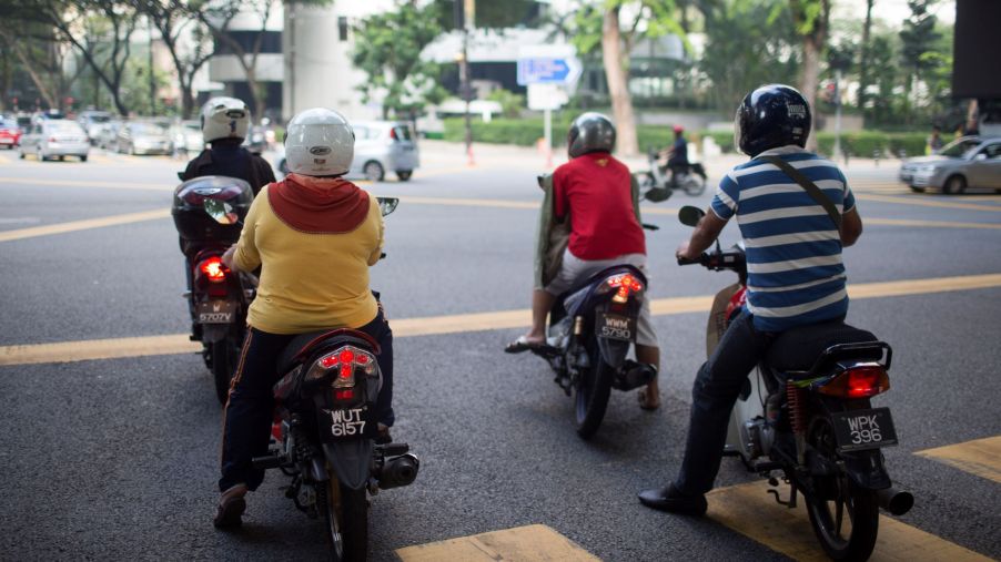 Motorcycle riders in Malaysia wait at a red light