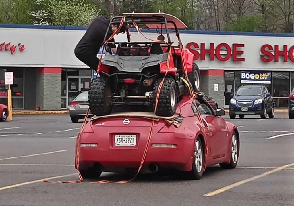 a red Nissan 350Z in a praking lot with a red side-by-side strapped onto the roof