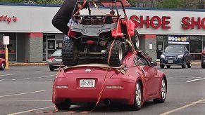 a red Nissan 350Z in a praking lot with a red side-by-side strapped onto the roof