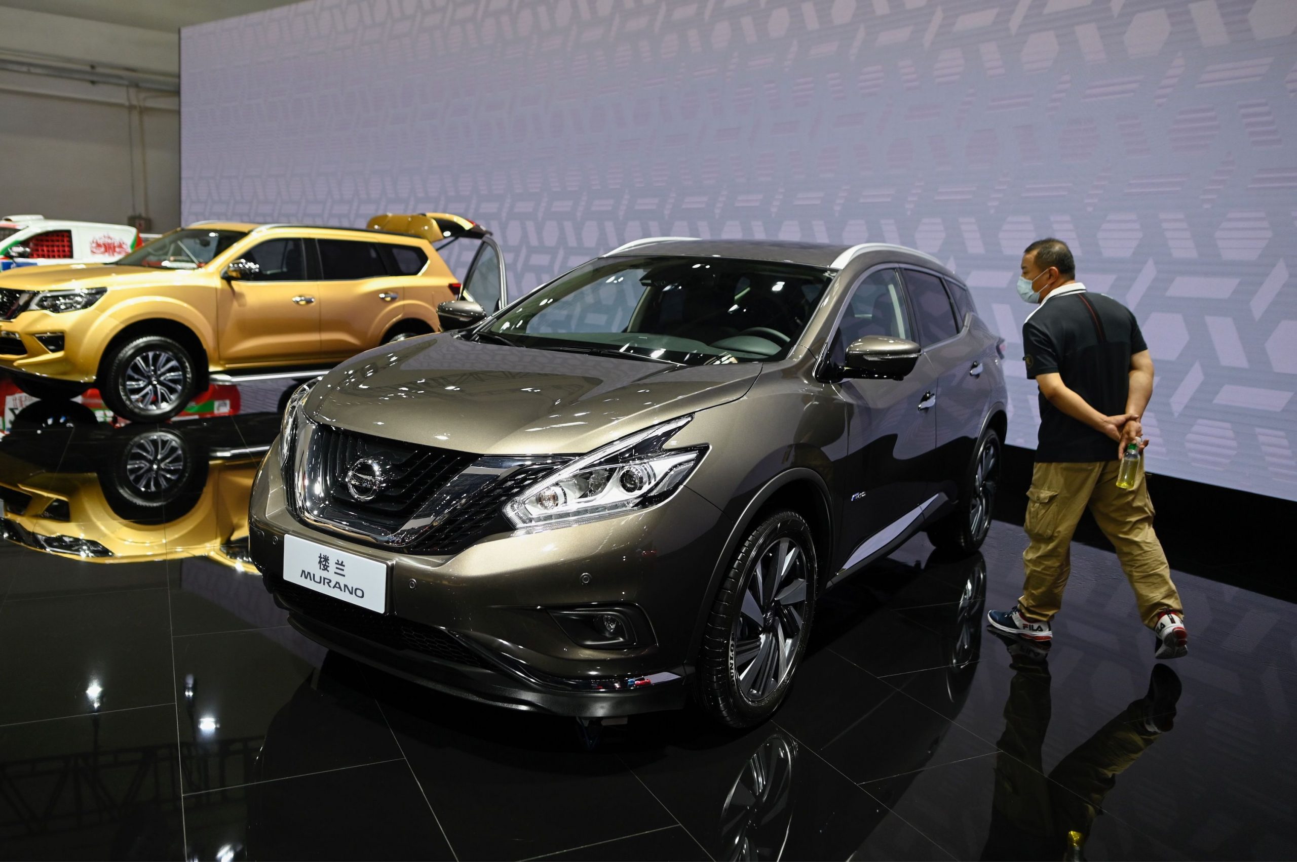 A man looks at a gray Nissan Murano car displayed at the Beijing Auto Show in Beijing