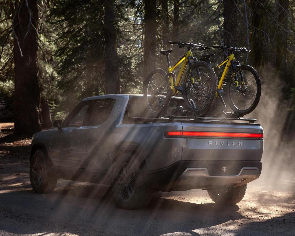Rivian R1T electric pickup truck parked in the woods with a bike on the back