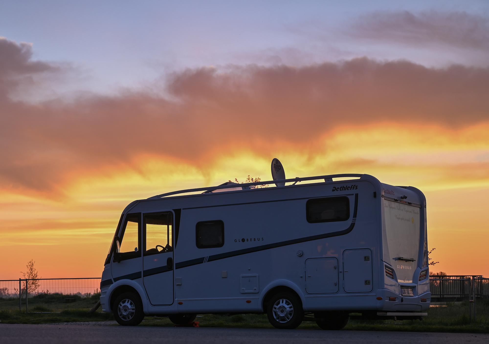 The sun rises behind a parked RV motorhome
