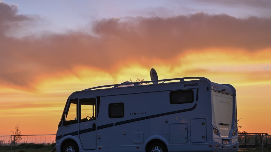 The sun rises behind a parked RV motorhome