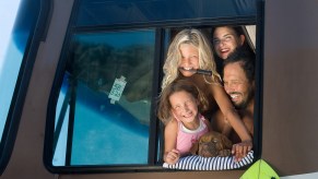 A man and woman RVing with their kids and a small brown dog