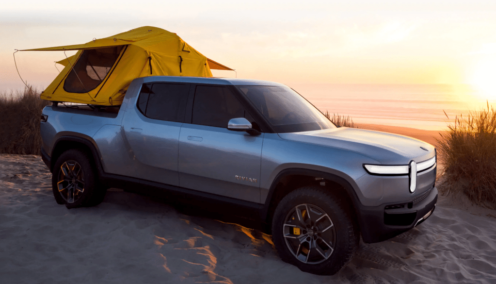 The 2021 Rivian R1T parked on the beach with a yellow tent on the back 