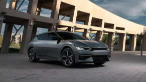 A dark colored 2022 Kia EV6 parked in front of a city building