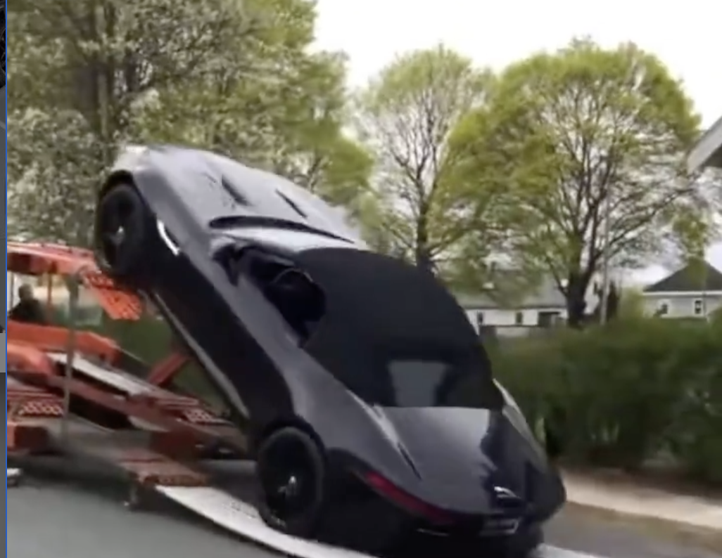 An iamge of a Jaguar F-Type falling from a trailer and crashing into a pickup truck.