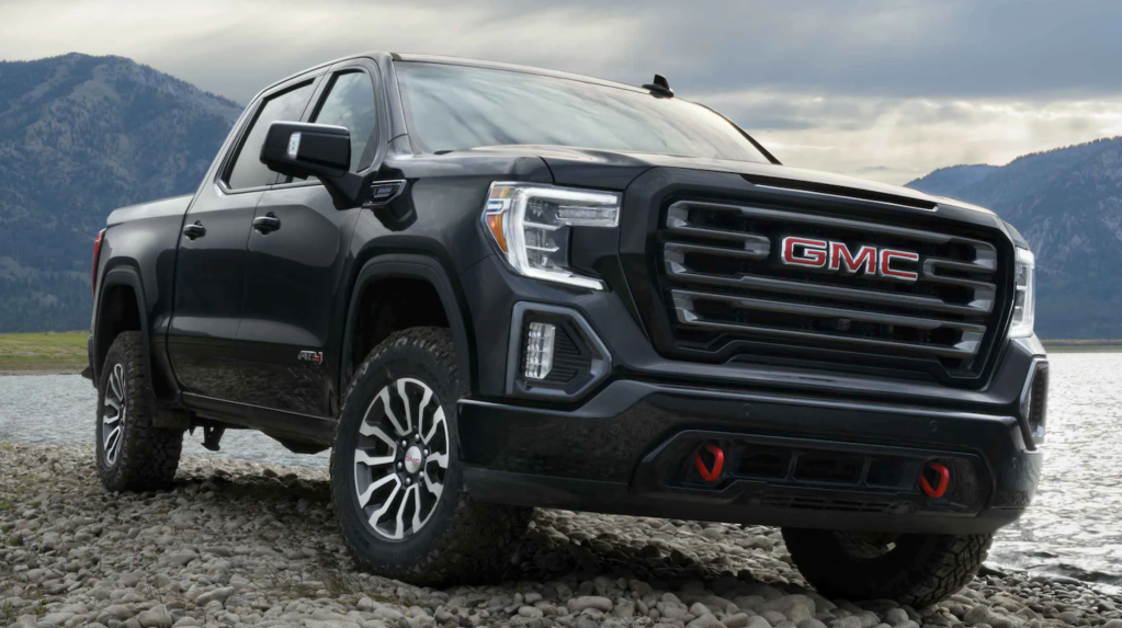 A black 2021 GMC Sierra AT4 parked in gravel in front of a lake 