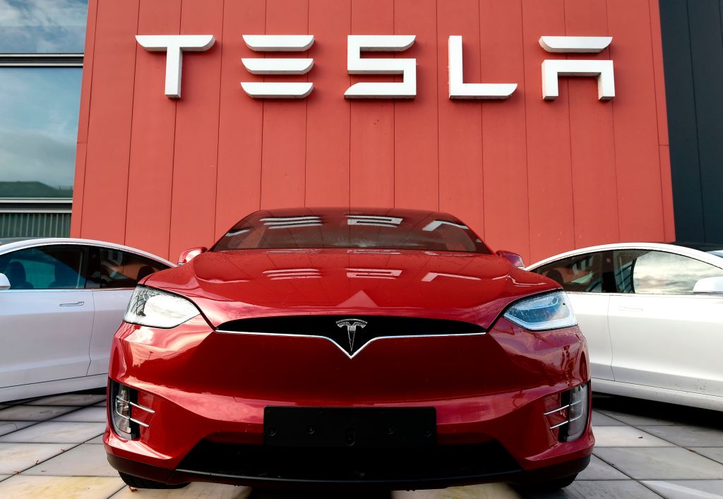 A red Tesla sits on a showroom floor.
