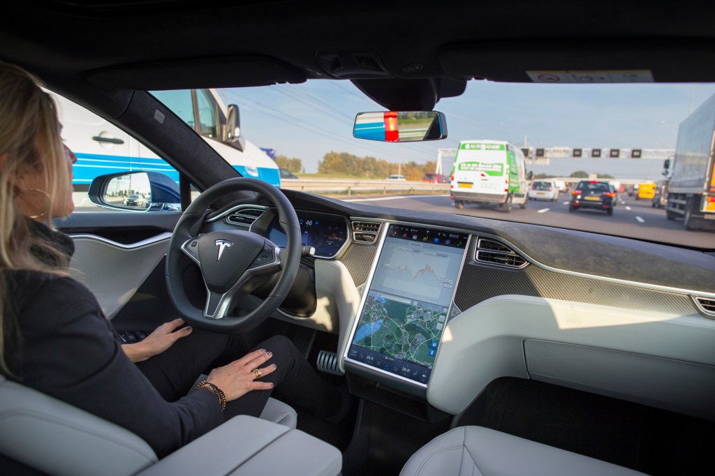 A woman uses Tesla Autopilot on the highway.