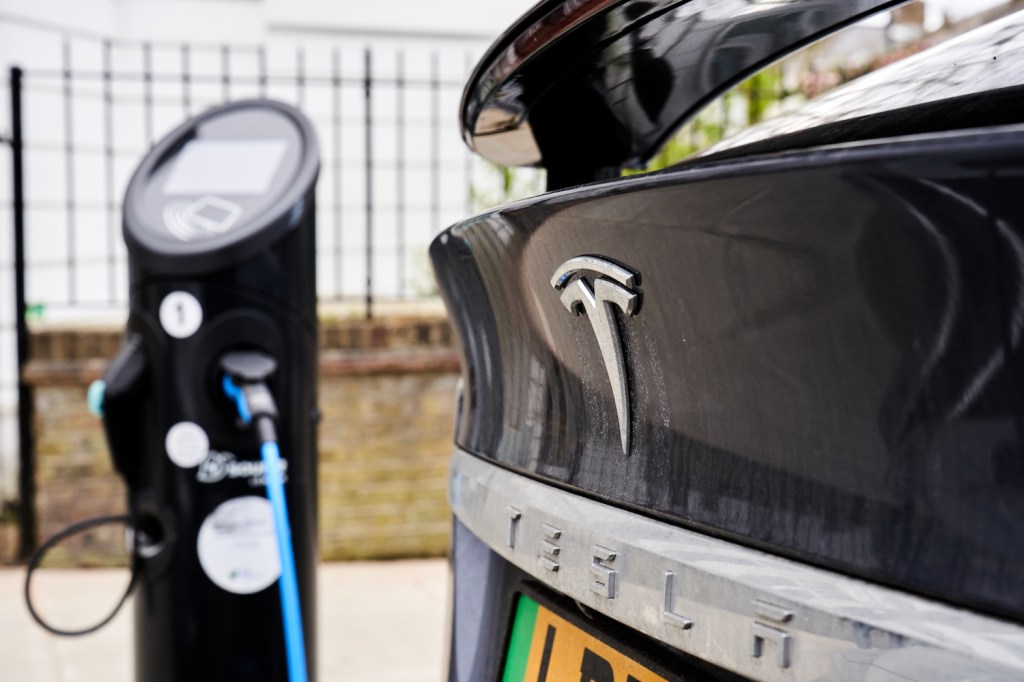 A Tesla plugged in at a charging station, multiple Tesla models are among the best-selling EVs