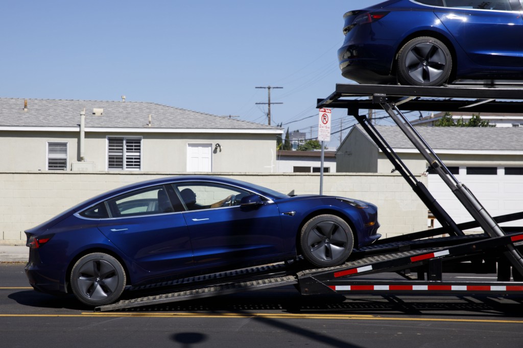 A Tesla Model 3 being loaded onto a car carried