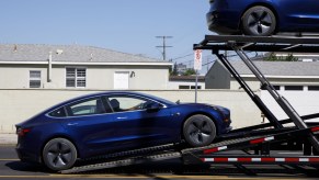 A Tesla Model 3 being loaded onto a car carried