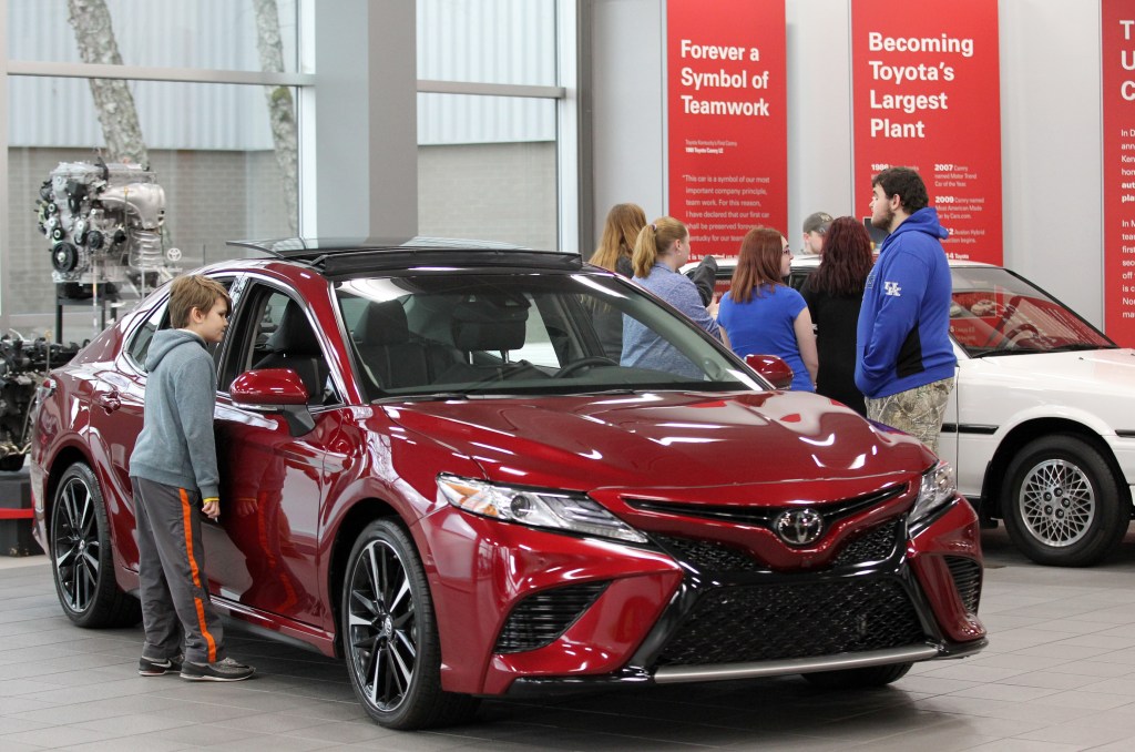 Visitors to the Toyota Motor Manufacturing plant look over the red 2019 Toyota Camry at the Georgetown plant