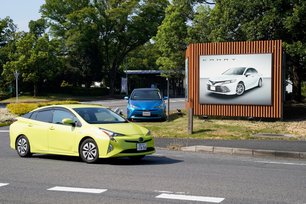 A blue Toyota Motor Corp's Prius vehicle drives past the company's Tsutsumi plant in Toyota City, Aichi Prefecture, Japan
