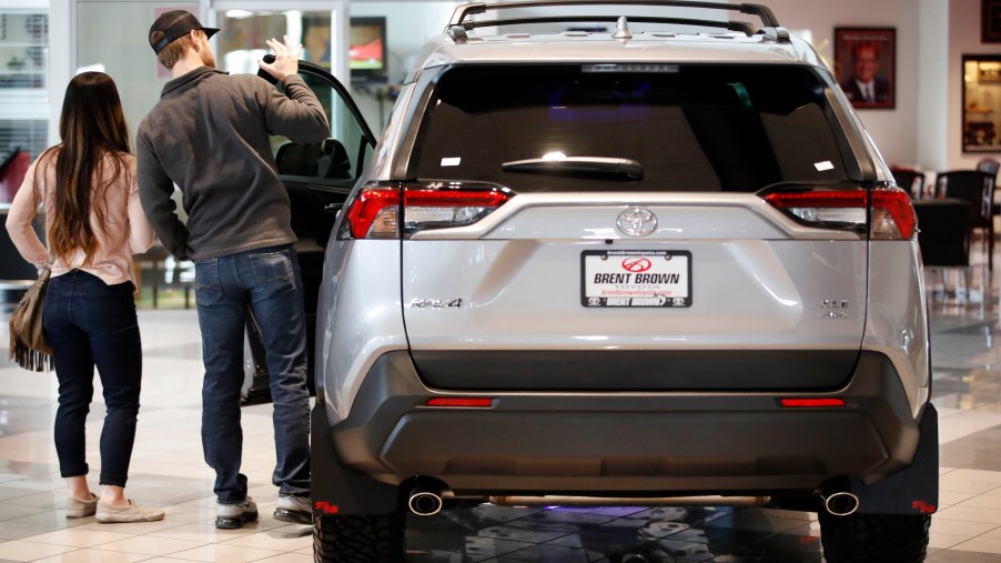Potential customers look at a silver Toyota Motor Corp. RAV4 sport utility vehicle (SUV) at the Brent Brown Toyota dealership