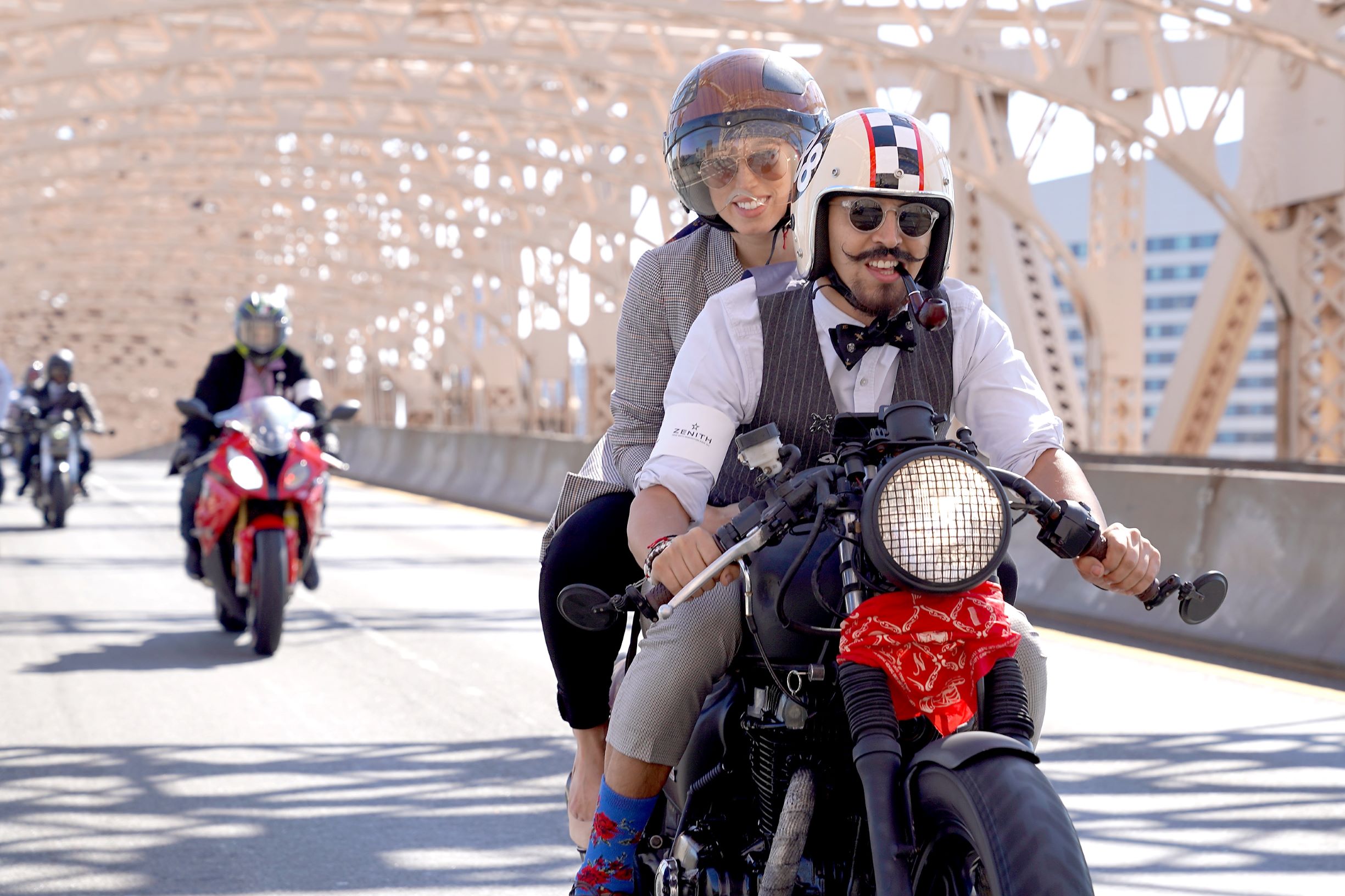 Two riders dressed in vintage clothing ride over a NYC bridge at the 2018 Distinguished Gentleman's Ride