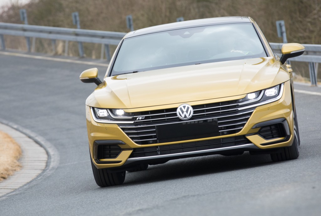 A gold VW Arteon performs a test drive near a Volkswagen manufacturing plant.