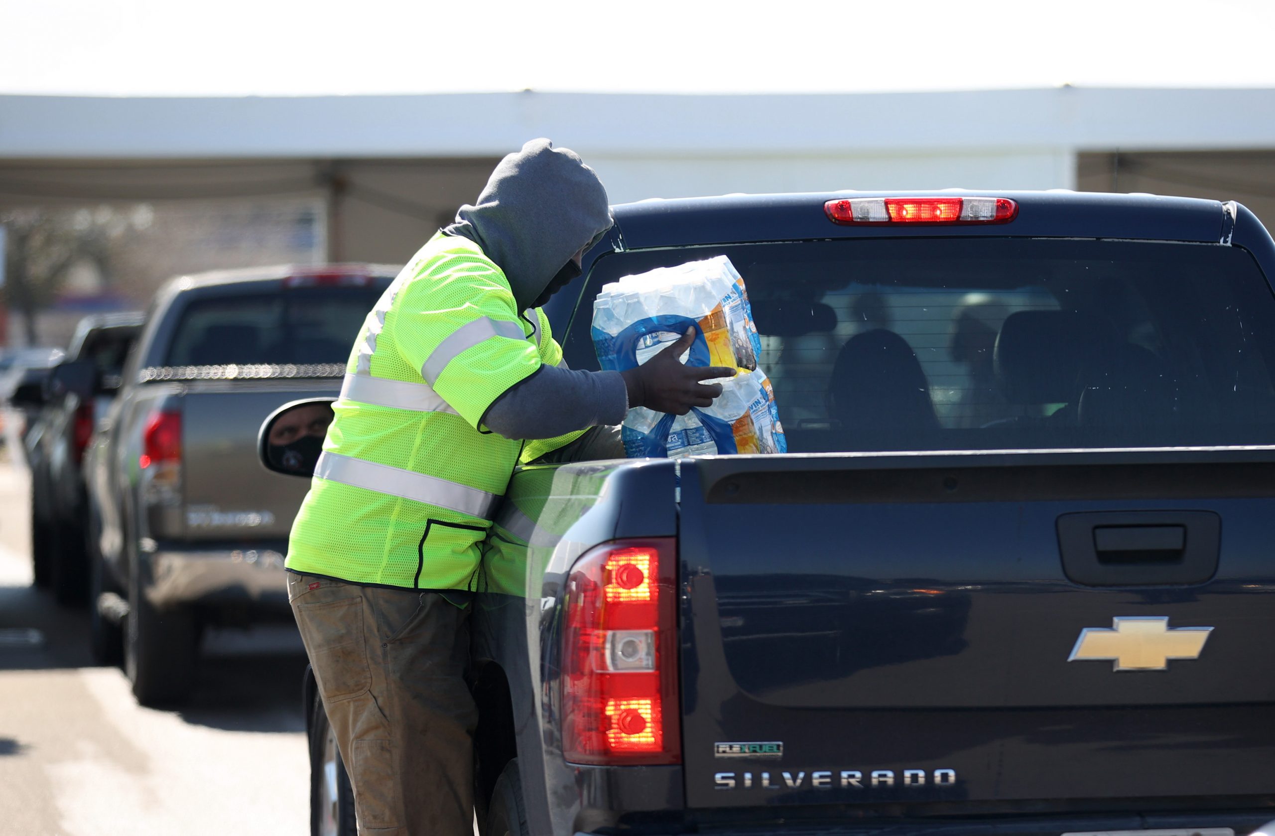 A worker with Houston Public Works loads a case of water into the truck bed of a Chevy Silverado during a mass water distribution