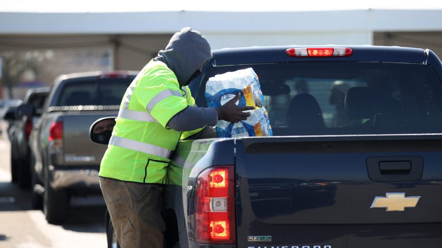 A worker with Houston Public Works loads a case of water into the truck bed of a Chevy Silverado during a mass water distribution