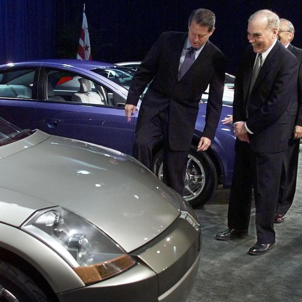 US Vice President Al Gore (L) kicks the tires of a concept car at an event showcasing cars from the Partnership for a New Generation of Vehicles (PNGV) in Washington, DC as General Motors Vice Chairman Harry Pearce (R) looks on.