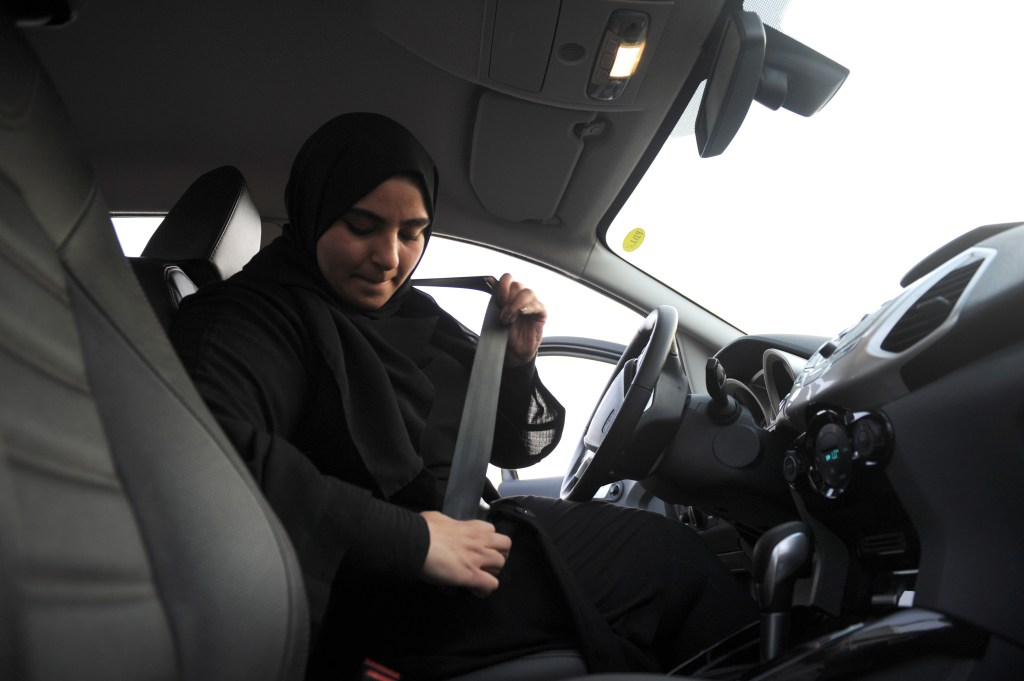 A woman buckles her seatbelt before driving