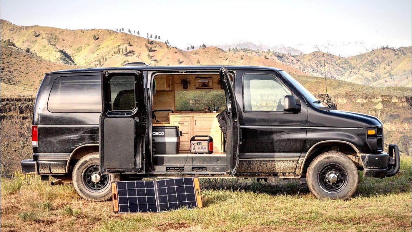 Chase Christopher's affordable camper van build, a black Ford Econoline parked in the hills