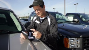 Car salesman Pete Argumaniz checks the VIN on a used car at Classic Buick-Pontiac-GMC in Arlington, Texas, on December 12, 2008