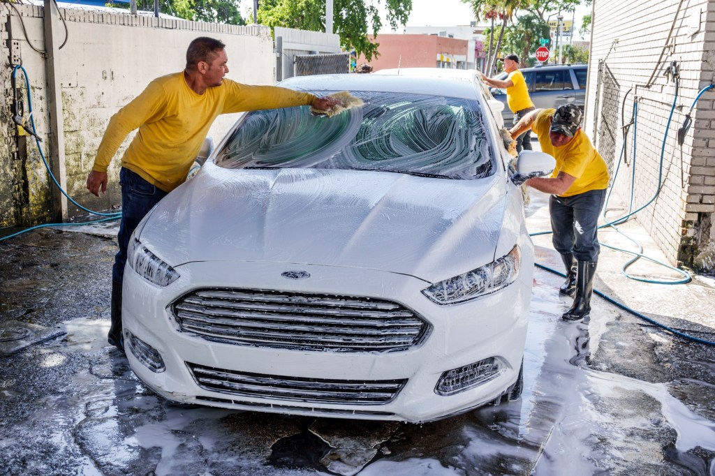 Two workers wash a car