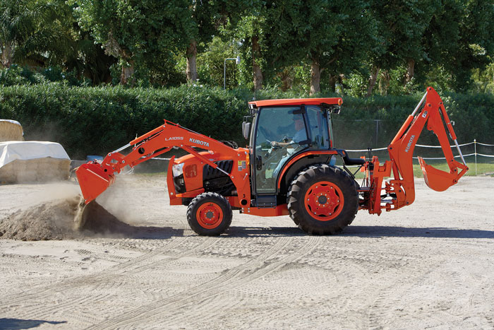 an orange Kubota compact tractor working in sand 