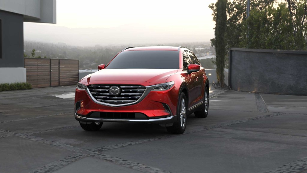 A red 2021 Mazda CX-9 parked in a drive way near a home