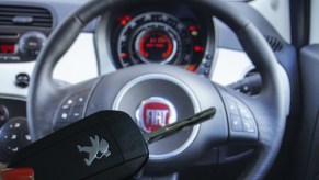 A woman holds a Peugeot car key as Fiat logo is seen behind in Ankara, Turkey on November 26, 2019. (Photo by Aytac Unal/Anadolu Agency/Getty Images)