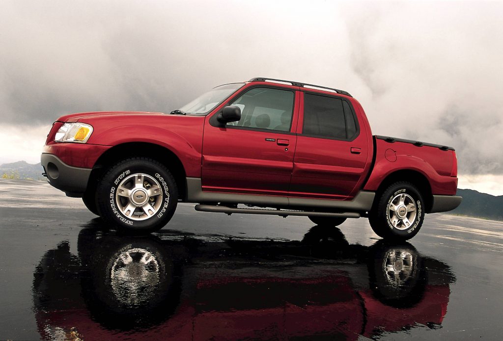 A red Ford Explorer Sport Trac pickup truck parked on wet sand