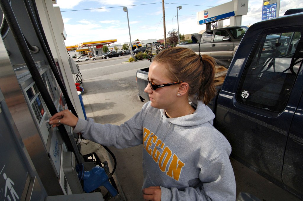 A customer slides her credit card into a gas pump as she prepares to fill her truck with gas at a Chevron station. 